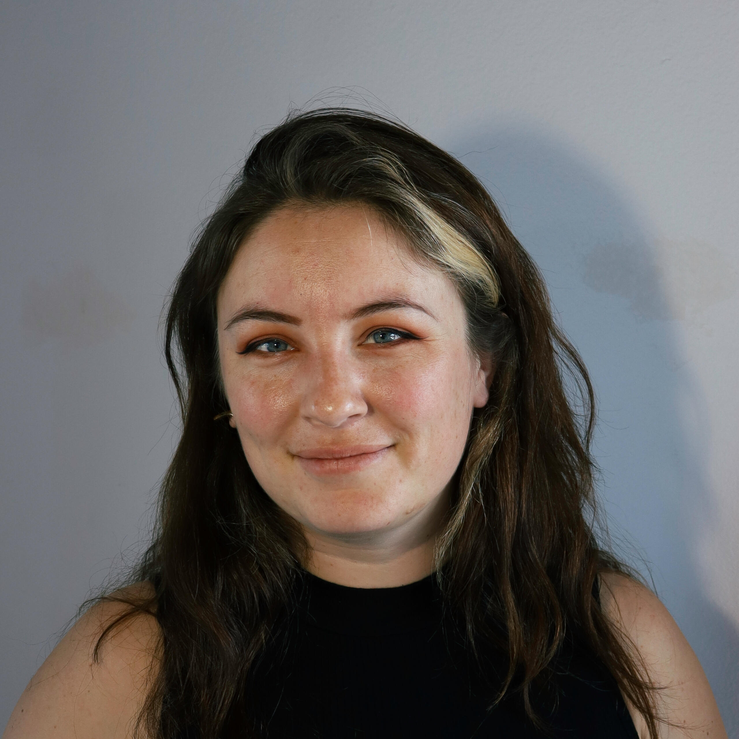 Image of Bailey Anderson. Woman with dark brown hair in black shirt smiling softly while looking at camera.