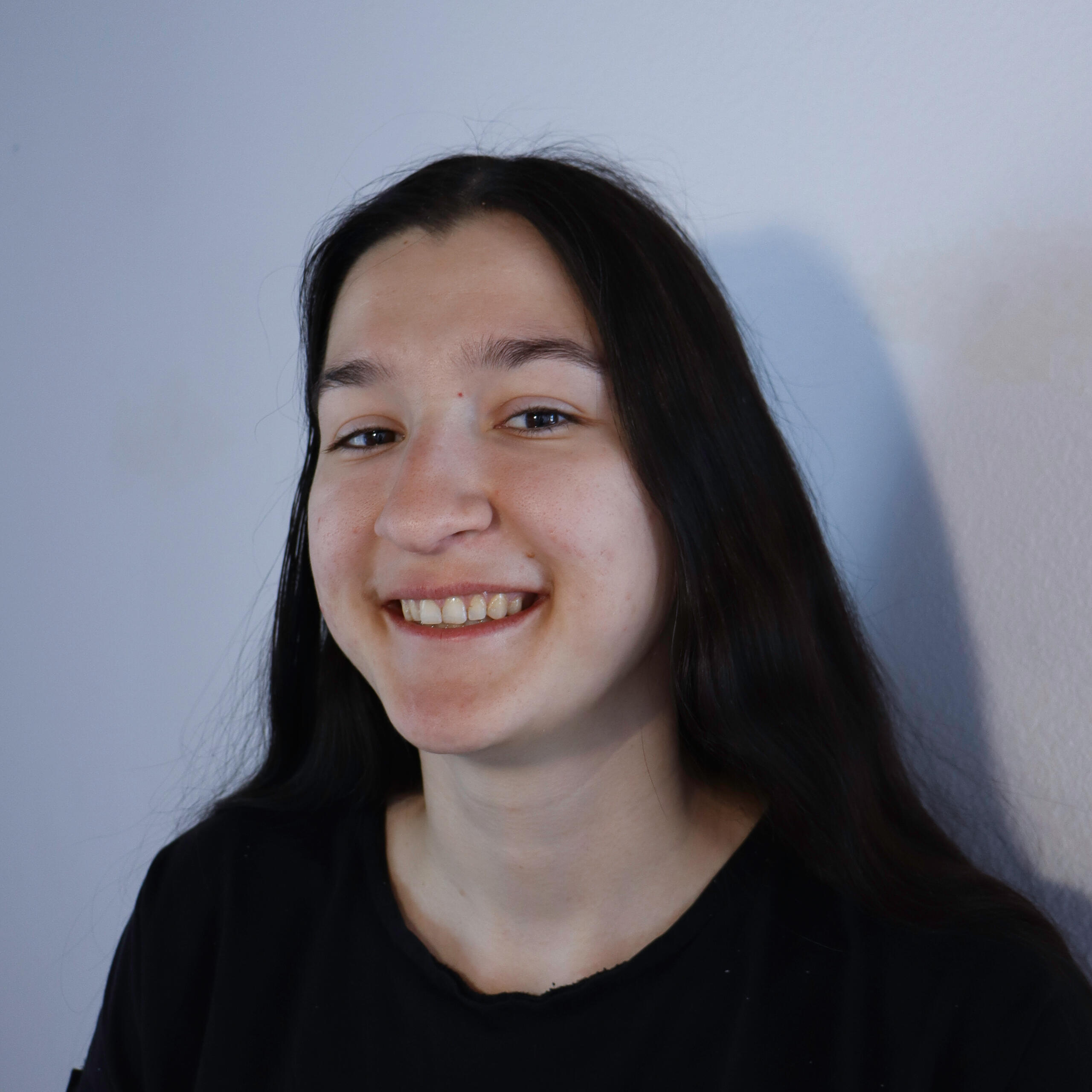 Image of Iulia Filipov-Serediuc. Woman with dark hair in black shirt with a wide smile while looking at camera.