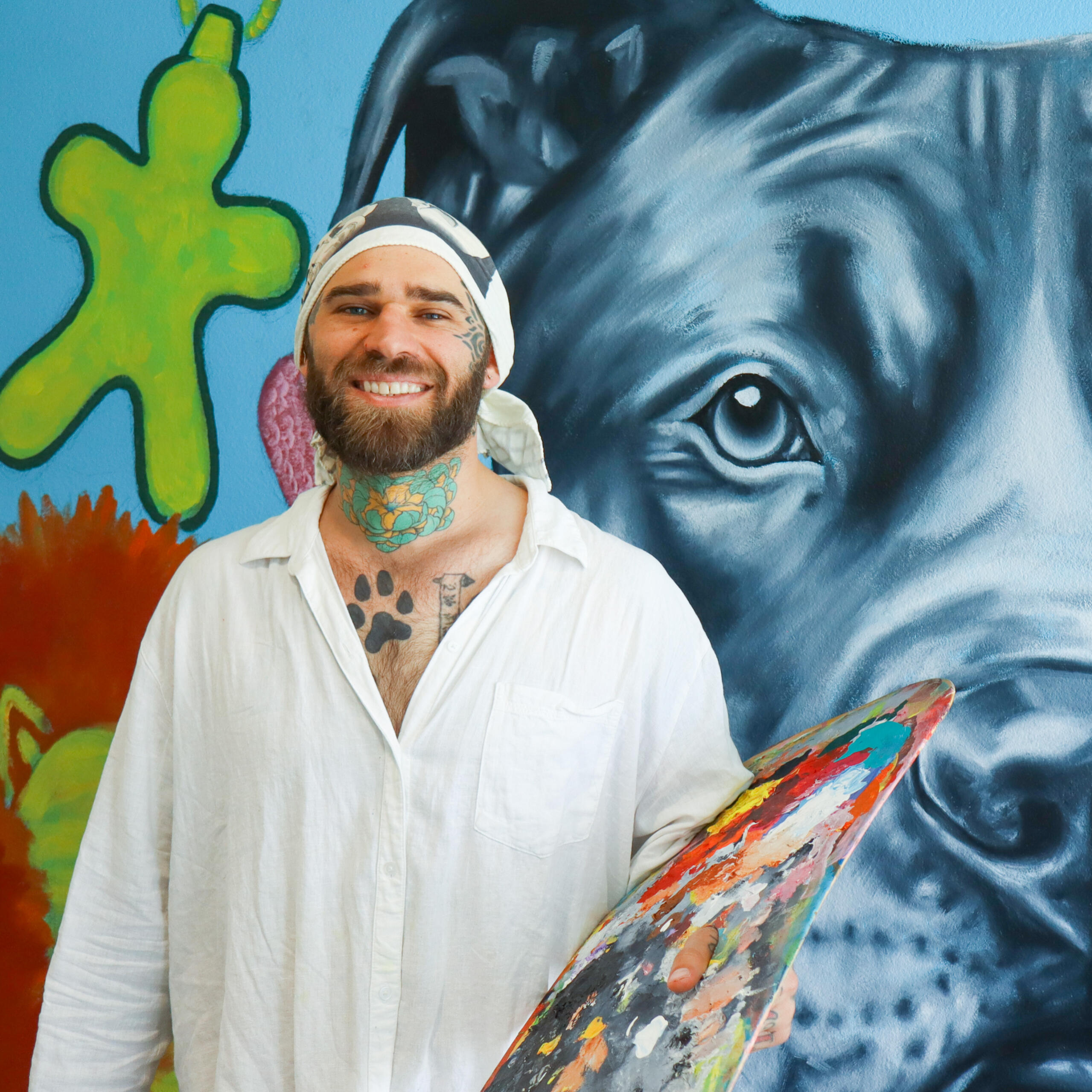 Image from Stone Soup event from 2023 Desert Biennial Project. Features bright orange diamond sign with black lettering spelling out Desert Biennial Project behind a sign made from dimensional lumber with Stone Soup painted in red on front of sign.